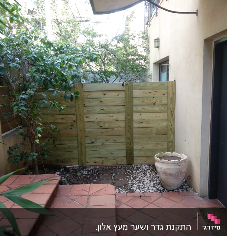 גדר עץ בגינה עם שביל אבנים ועציץ ריק